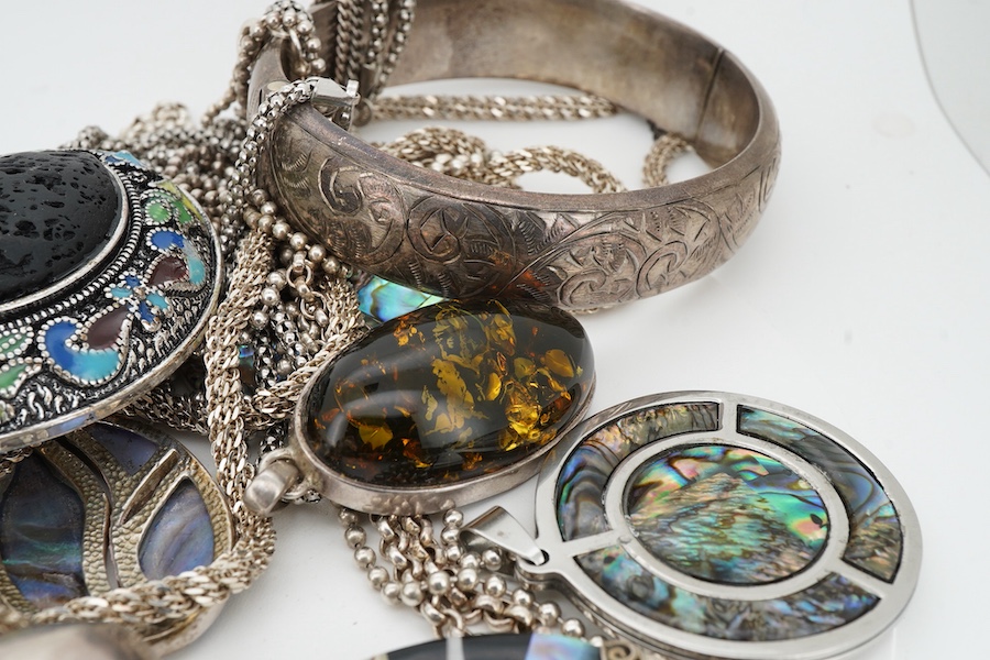 A collection of silver and costume jewellery, comprising: a pendant designed as an elephant; an enamel and porous black stone pendant; five shell medallion pendants; two paste pendants; and a treated amber pendant; all w
